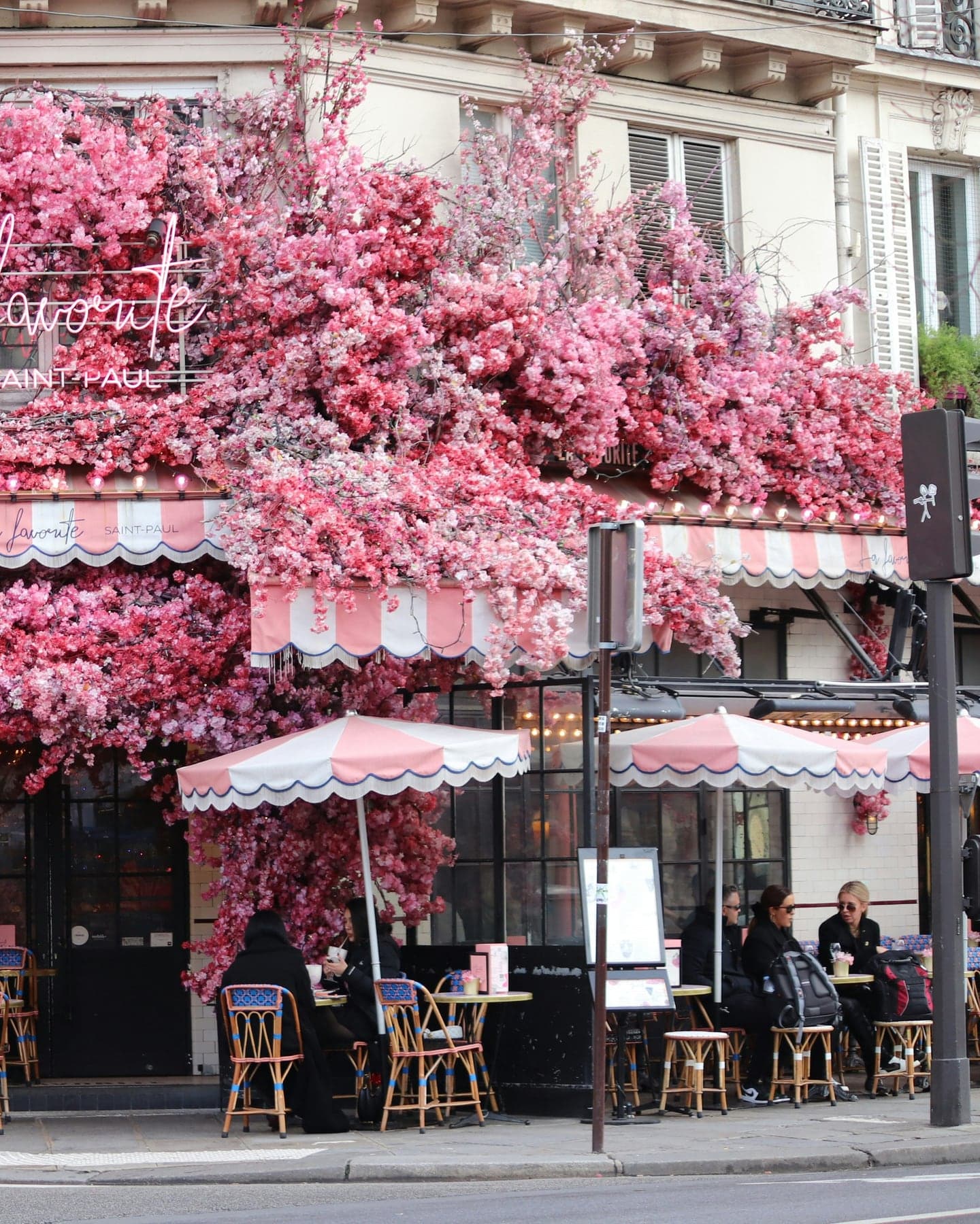 Cafe parisien tres fleuri avec facade rose et terrasse