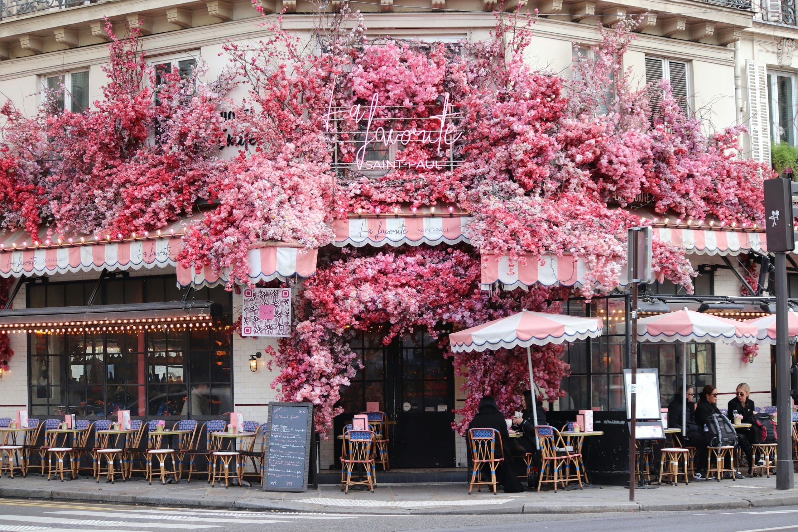 Cafe parisien tres fleuri avec facade rose et terrasse